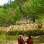Couple sitting along the Fremont River in Capitol Reef